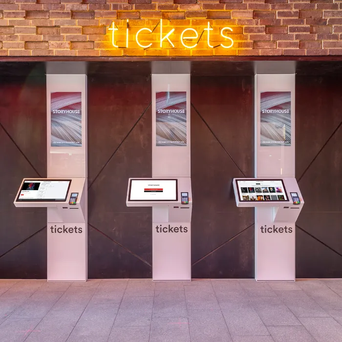 Three Storyhouse ticket kiosks under the neon tickets sign in the foyer